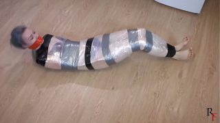 Barefoot Astrid is tightly wrapped with film and tape